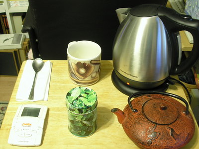 [Clockwise, starting at noon—tea cup, electric kettle, tea pot, loose leaf green tea, timer, tea spoon]