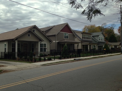 [Four newly build houses in a row, all different.] Black wrought iron fencing is the new white picket fencing.