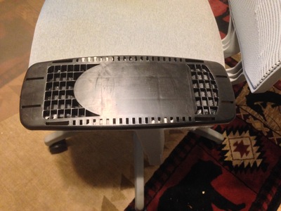 [Closeup of an uncovered arm on the office chair showing a surface with cutouts to save material, but makes it uncomfortable to use as an arm rest.] It's a combination arm rest and cheese grater!